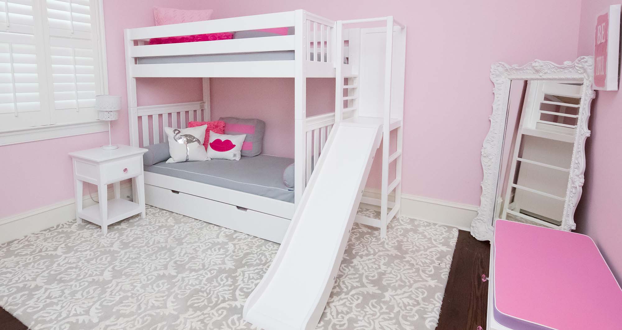 Phòng ngủ màu hồng với giường tầng tích hợp cầu tuột làm đồ chơi cho bé